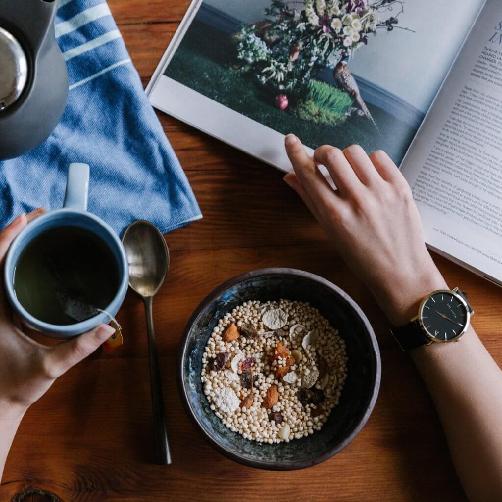 View from above of table with person with coffee, cereal, and a magazine