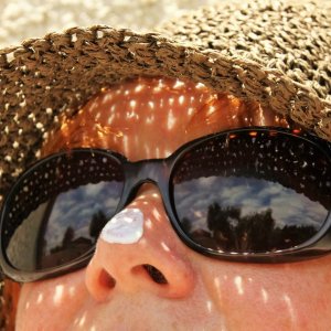 a women with sunscreen on her nose, wearing a hat and sunglasses