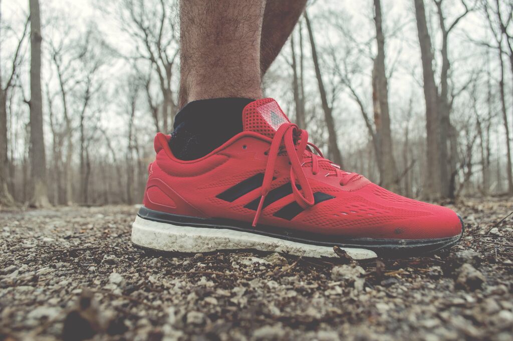 shot of a man's red running shoe in the forest