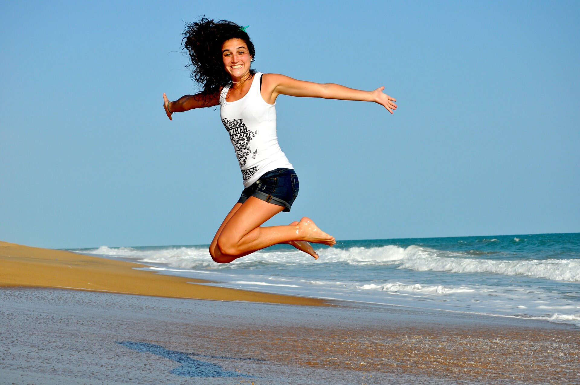 a young girl jumping in the air on a beach