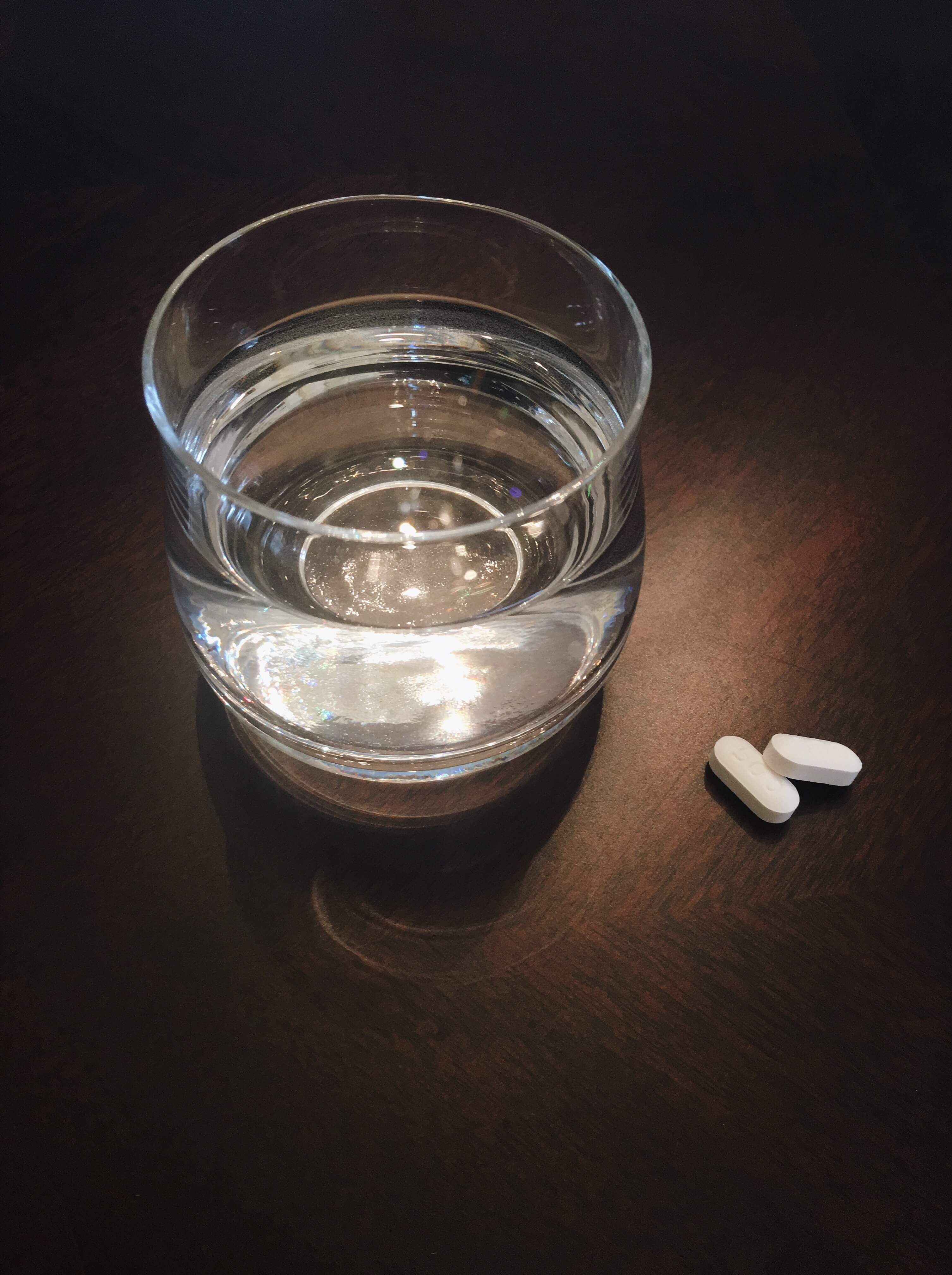 a glass of water and two white pills